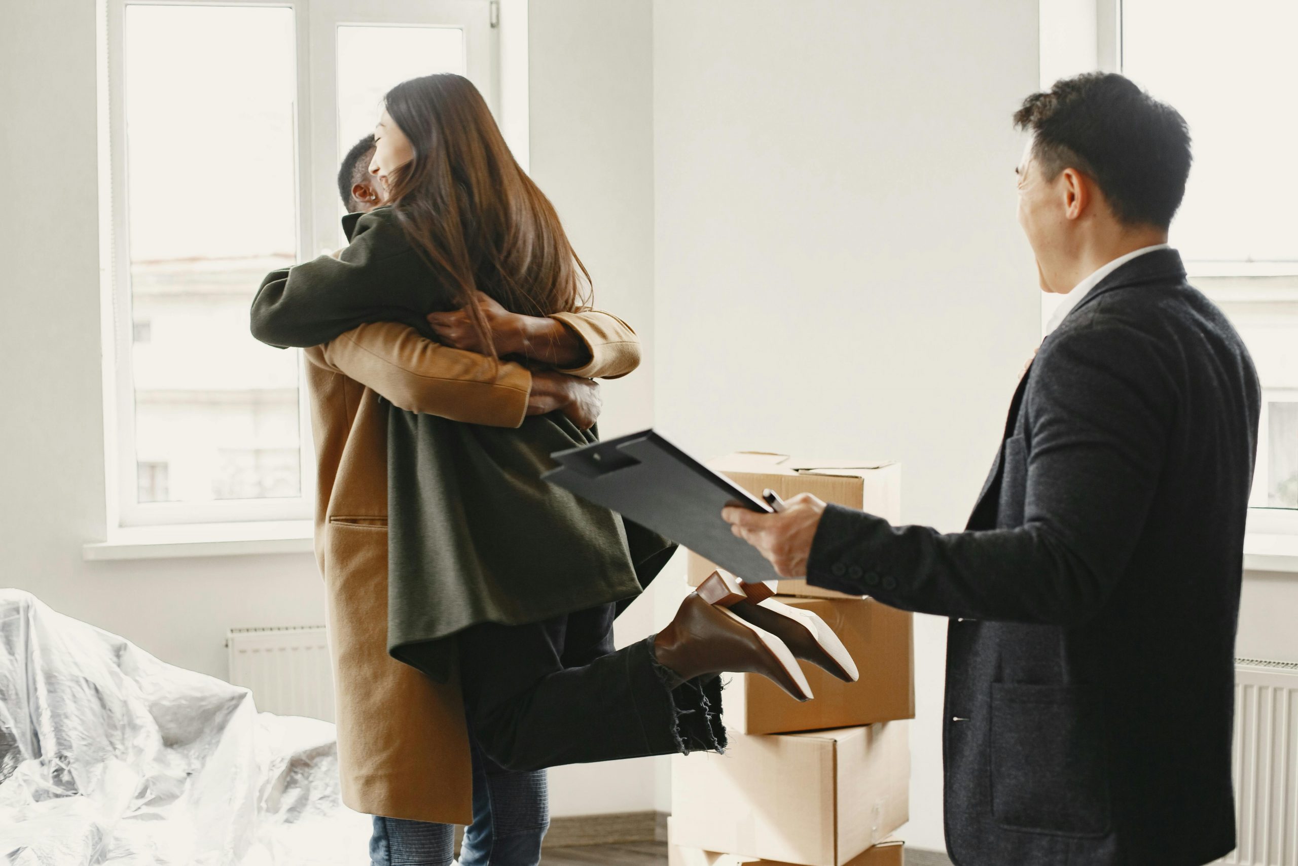 First-time homebuyers experience high levels of excitement and hug after purchasing their home, with their realtor standing by their side.