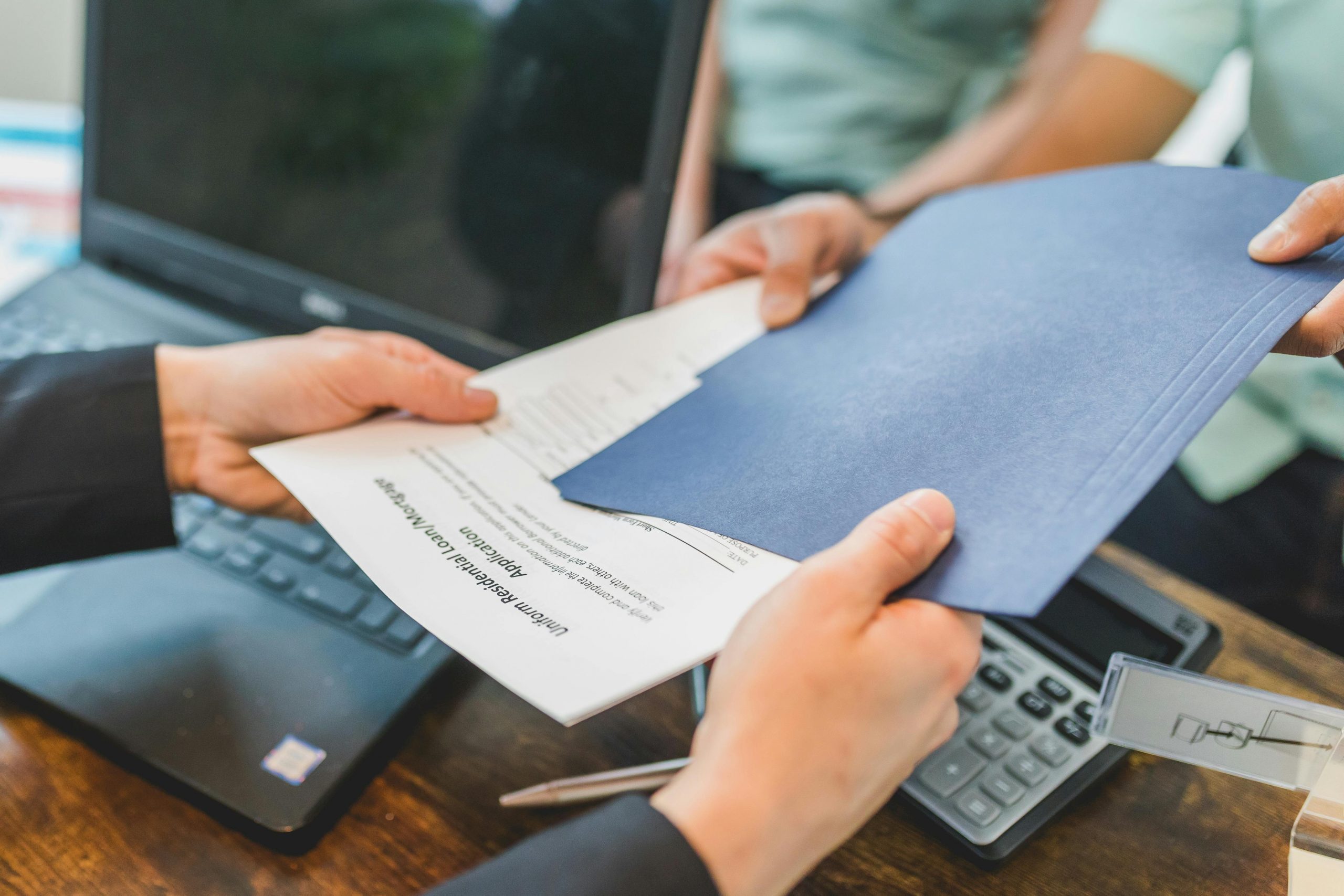 Real estate agent handing a printed-out "residential loan/mortgage" document to a buyer. 